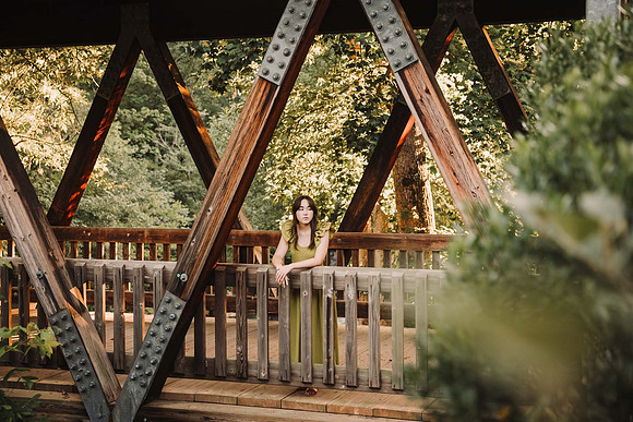high school senior looking out from a historic wooden bridge