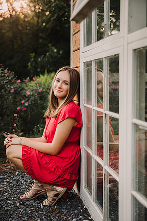 Teen girl leaning against a reclaimed wood greenhouse