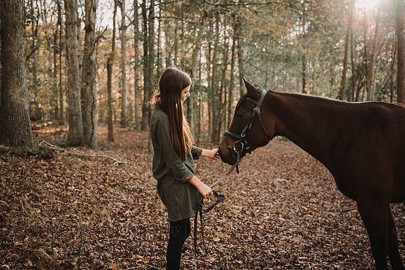 girl admires her horse in a forest