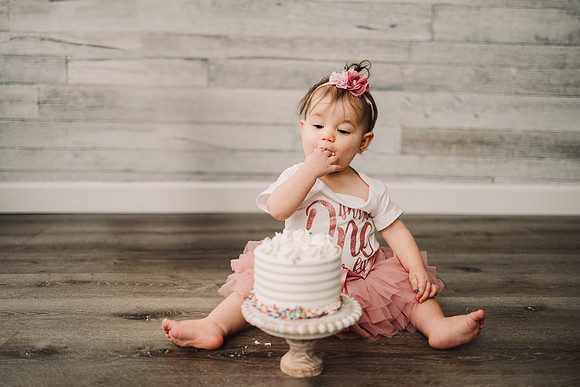 One year old eating a birthday cake with her hands