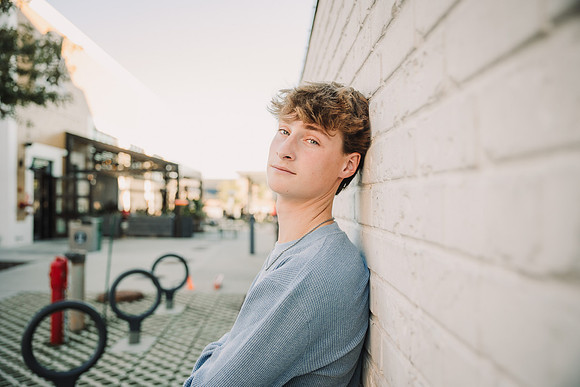 Color image of a teen boy leaning against a wall
