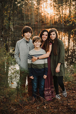 mom and her three kids stand in front of a lake