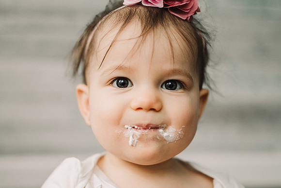 baby with her faced covered with cake icing