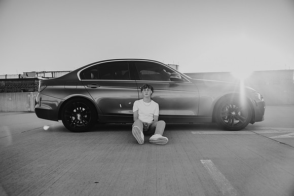 black and white image of a teen boy with his car on a roof top at sunset