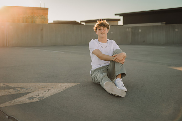Young man sits on the roof top of a parking lot