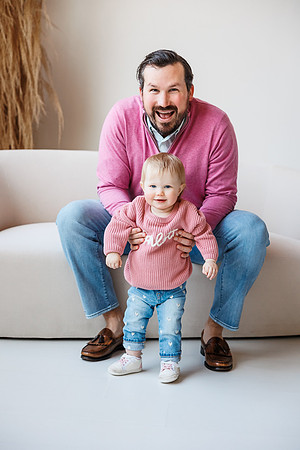 daddy proudly helps one year old daughter stand at a photo session