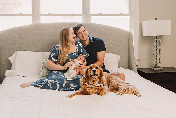dog laying on bed with young family