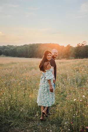 Couple walking away on a flower field at sunset