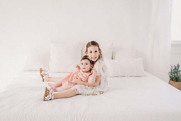 Sisters sitting on a bed in a roswell studio