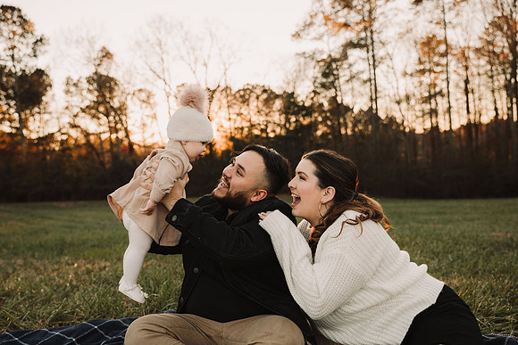 loving father holds up baby while mom looks on