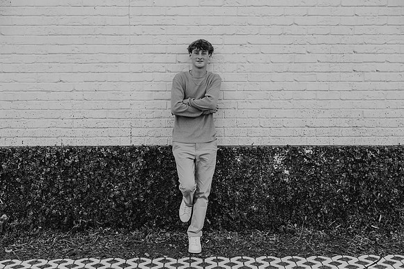 Teen boy leans against a brick wall