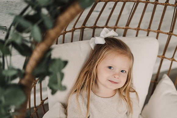 little girl smiles while sitting in a egg chair