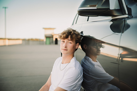 portrait of a teen boy leaning against his car