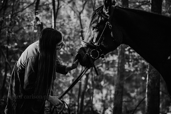 black and white image of a girl petting her horses nose