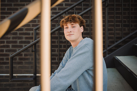 young man sits on stairs at halcyon and looks between bars